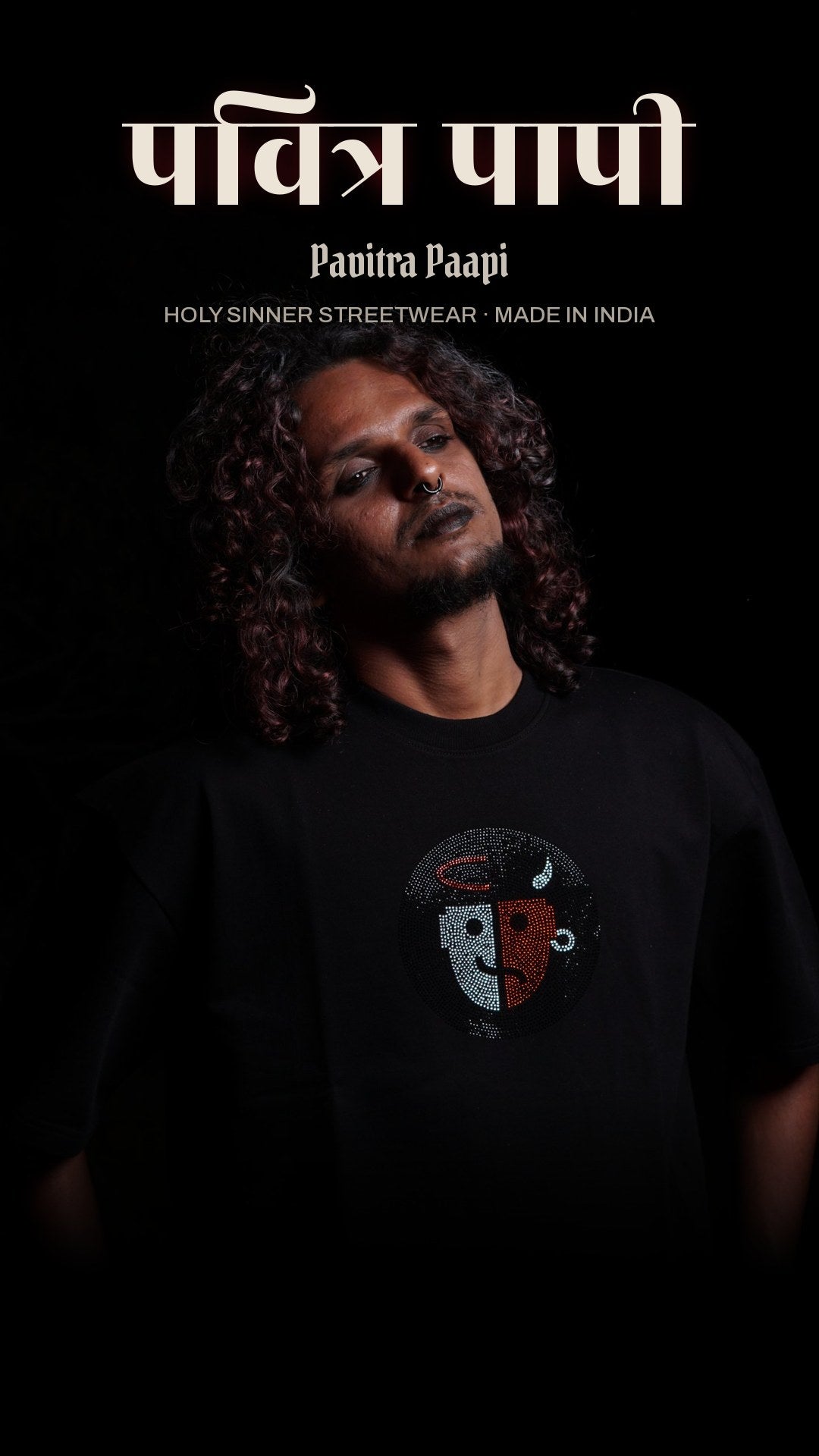 Pavitra Paapi model in a black oversized tee with the rhinestone saint and sinner face